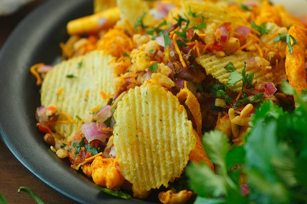A vibrant mixed snack chaat made with kurkure, namkeen, chips, gathiya, sev, tomatoes, onions, coriander and lemon, served fresh in a rustic Indian style.