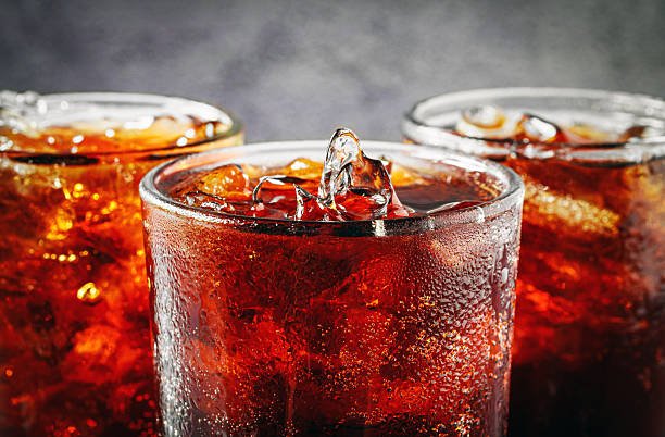 Cola soft drink with ice cubes, soda fizzy drink in Cold three glass on gray background, close-up