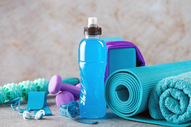 Drink isotonic bottle and fitness equipment on a grey background. Sport, fitness or yoga concept